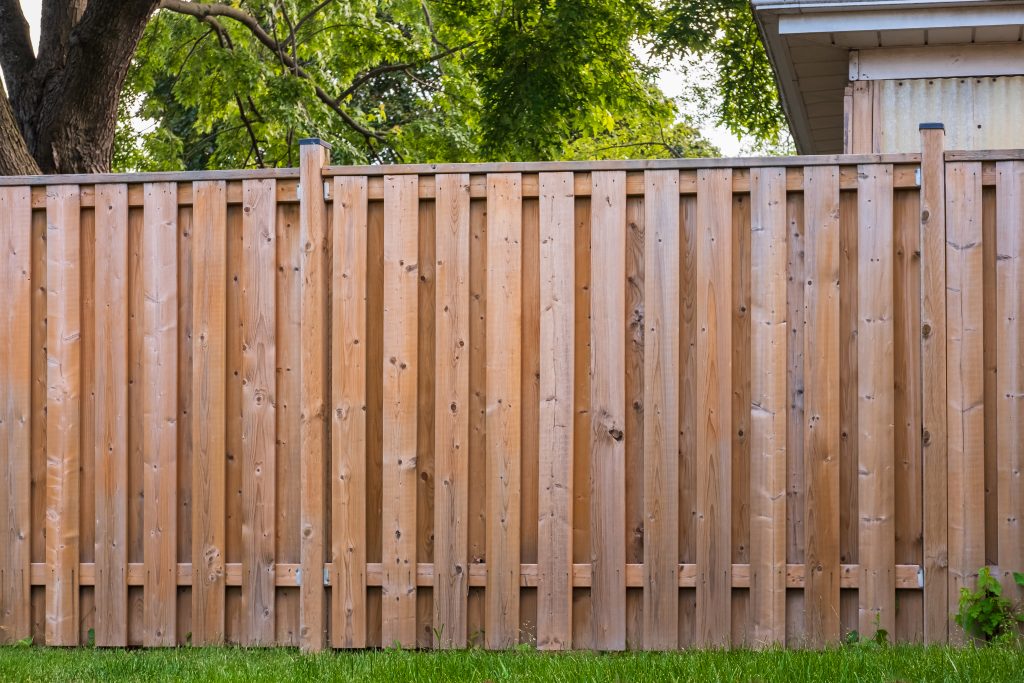 Nouvelle clôture en bois autour de la maison. Clôture en bois avec pelouse verte.